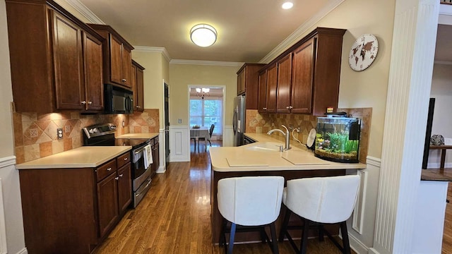 kitchen featuring appliances with stainless steel finishes, dark hardwood / wood-style flooring, ornamental molding, sink, and a breakfast bar area