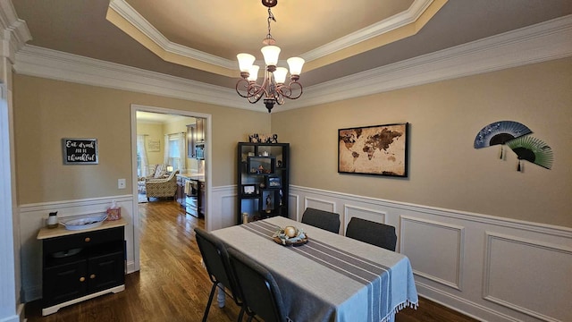 dining room with a raised ceiling, ornamental molding, dark hardwood / wood-style floors, and a notable chandelier