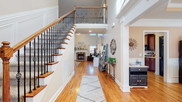 entrance foyer featuring a healthy amount of sunlight, ornamental molding, a fireplace, and light hardwood / wood-style flooring