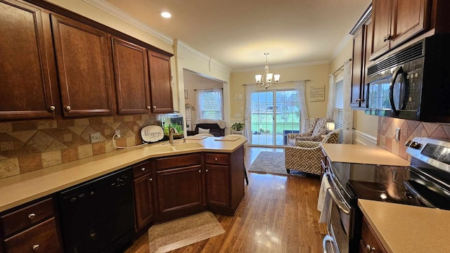 kitchen featuring dark wood-type flooring, black appliances, crown molding, sink, and a notable chandelier