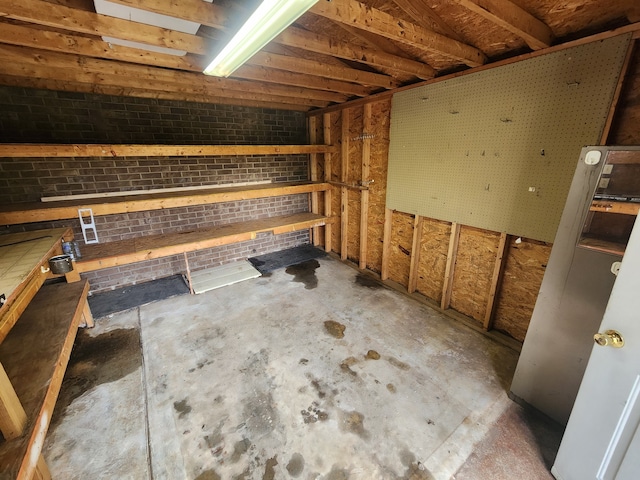 interior space with concrete flooring, a workshop area, and brick wall