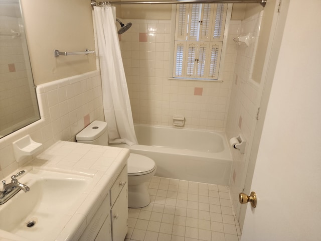 full bathroom with shower / bathtub combination with curtain, tile patterned floors, toilet, vanity, and tile walls