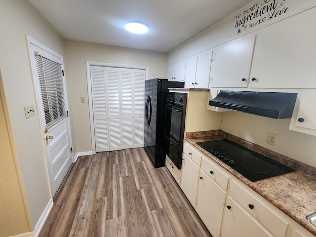 kitchen with black appliances, light hardwood / wood-style floors, white cabinetry, and extractor fan