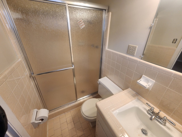 bathroom with tile patterned floors, sink, toilet, tile walls, and a shower with shower door