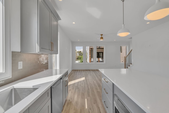 kitchen with dishwasher, light wood-type flooring, gray cabinets, and hanging light fixtures