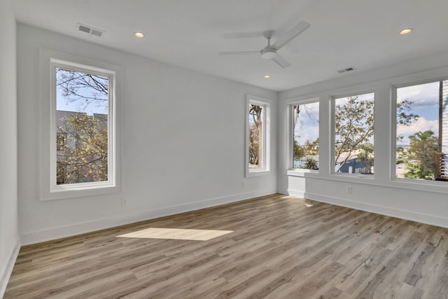 empty room with light hardwood / wood-style floors, ceiling fan, and a healthy amount of sunlight