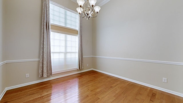 unfurnished room with hardwood / wood-style floors, ornamental molding, and an inviting chandelier