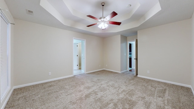 spare room featuring ceiling fan, light colored carpet, and a tray ceiling