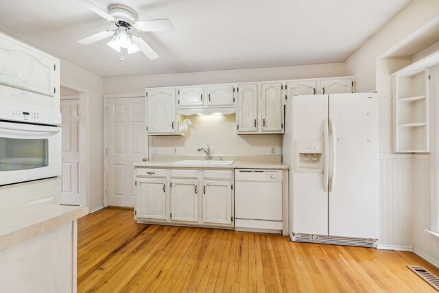 kitchen featuring white appliances, sink, light hardwood / wood-style flooring, ceiling fan, and white cabinetry