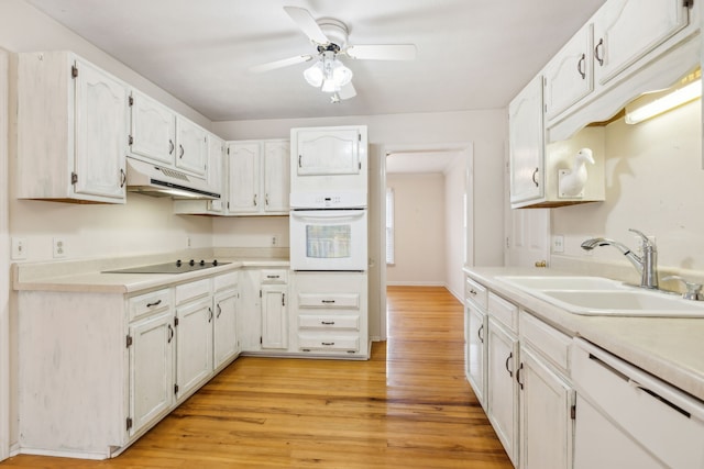 kitchen featuring white appliances, light hardwood / wood-style floors, white cabinetry, and sink