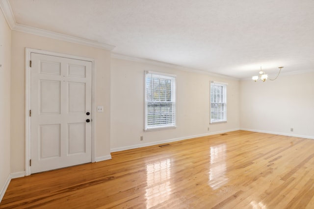 empty room with hardwood / wood-style floors, ornamental molding, and a chandelier