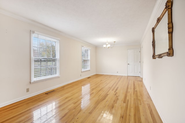 empty room featuring a chandelier, ornamental molding, a textured ceiling, and light hardwood / wood-style flooring