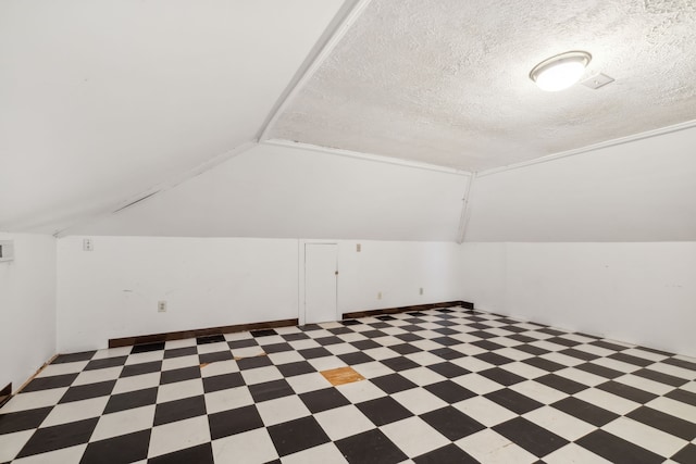 additional living space featuring a textured ceiling and vaulted ceiling