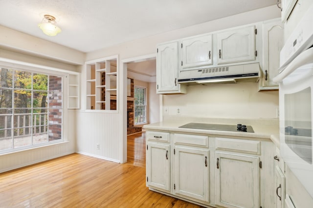 kitchen with white cabinetry, white oven, black electric cooktop, and light hardwood / wood-style flooring