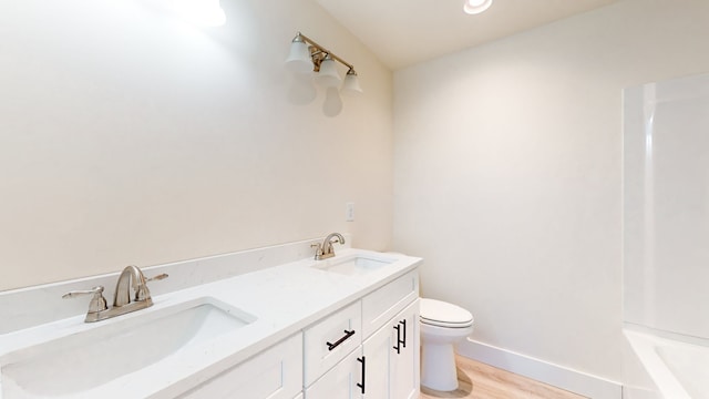 bathroom with a tub, vanity, wood-type flooring, and toilet