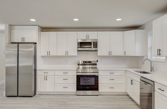 kitchen featuring white cabinets, sink, stainless steel appliances, and light hardwood / wood-style flooring