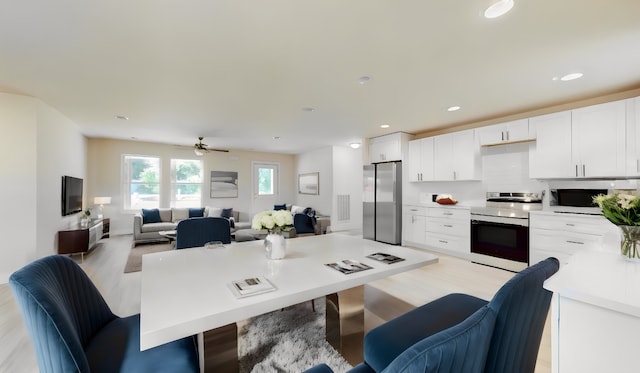 kitchen featuring ceiling fan, stainless steel appliances, light hardwood / wood-style flooring, a breakfast bar, and white cabinets