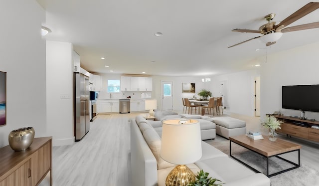 living room featuring light hardwood / wood-style flooring, ceiling fan, and sink