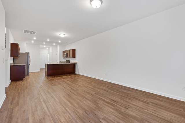 interior space with light hardwood / wood-style floors, kitchen peninsula, and appliances with stainless steel finishes