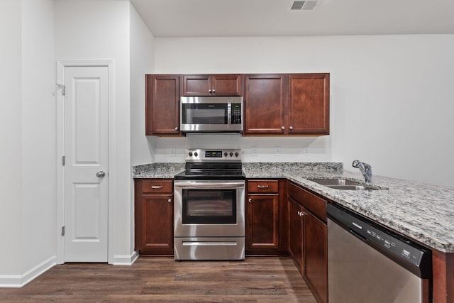 kitchen with sink, light stone countertops, stainless steel appliances, and dark wood-type flooring