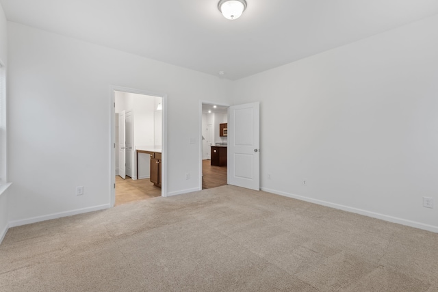 unfurnished bedroom with ensuite bathroom and light colored carpet