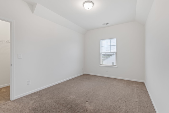 carpeted empty room featuring lofted ceiling