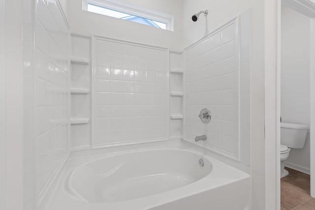 bathroom featuring washtub / shower combination, tile patterned flooring, and toilet