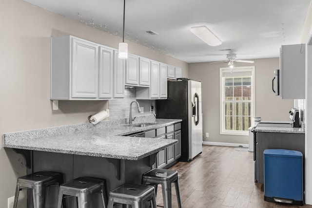 kitchen with a breakfast bar, white cabinetry, sink, and kitchen peninsula