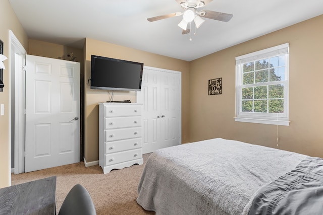 bedroom with ceiling fan, a closet, and light carpet