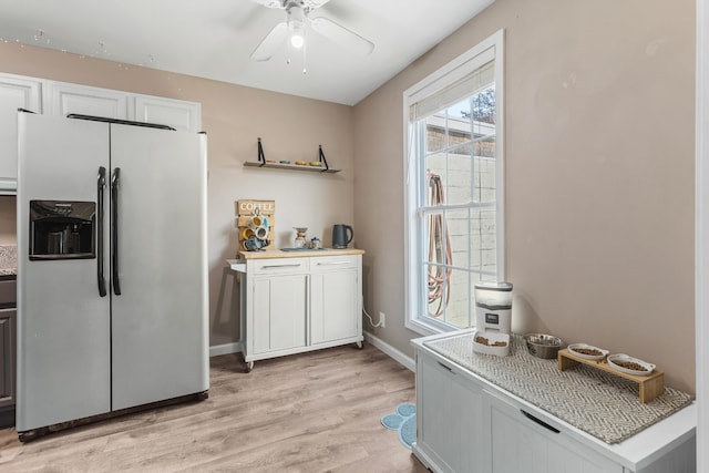 kitchen with ceiling fan, white cabinetry, light wood-type flooring, and stainless steel fridge with ice dispenser