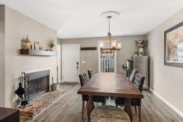 dining area with a fireplace, a notable chandelier, and hardwood / wood-style flooring