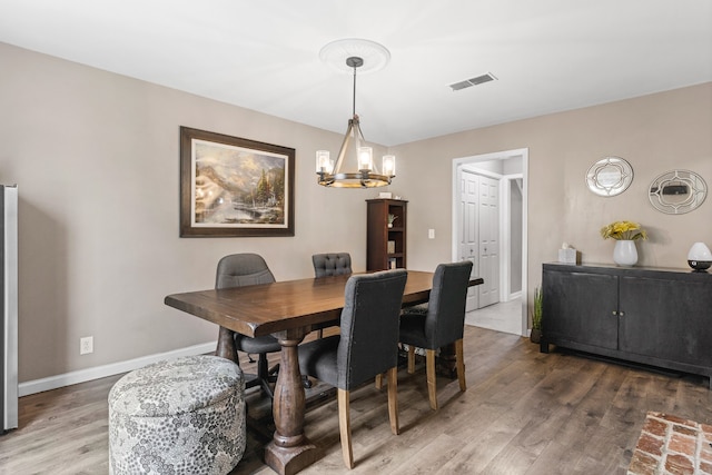 dining space with hardwood / wood-style flooring and a notable chandelier