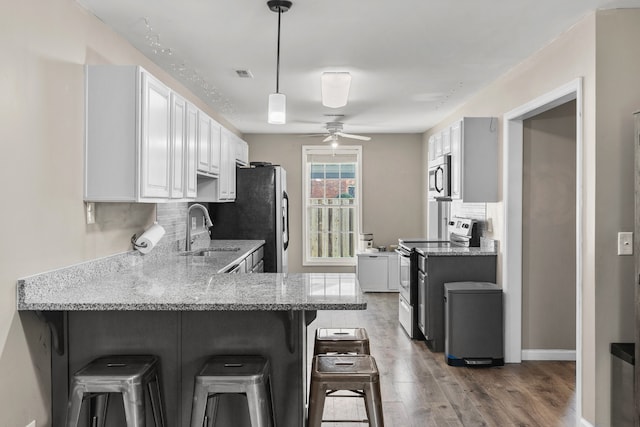 kitchen featuring sink, stainless steel appliances, kitchen peninsula, a breakfast bar area, and white cabinets