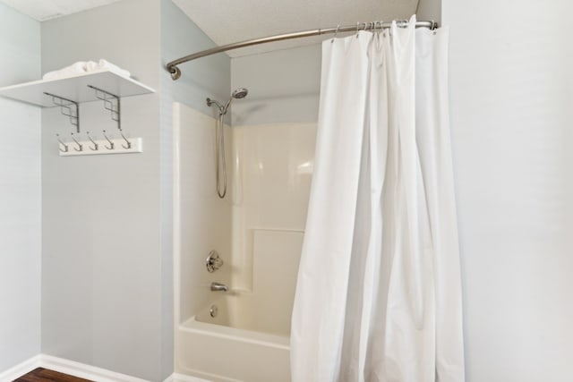 bathroom with hardwood / wood-style flooring, a textured ceiling, and shower / tub combo