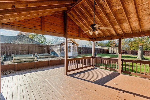 wooden deck with ceiling fan and a shed