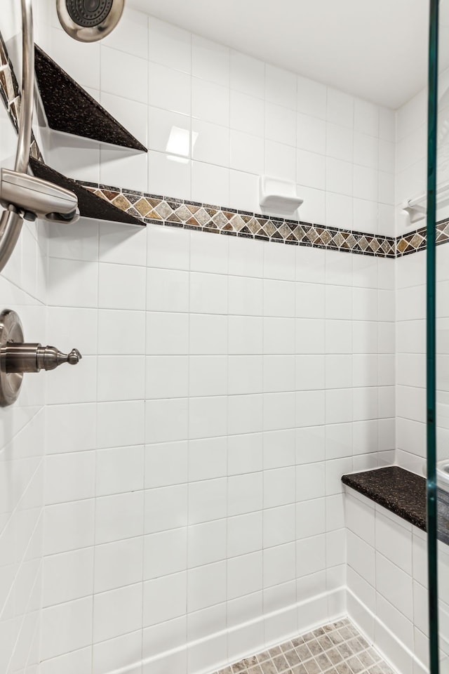 bathroom with tiled shower and tile patterned flooring