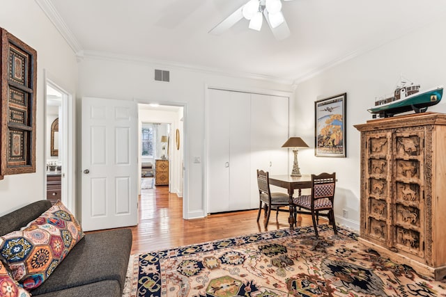 living area with ceiling fan, crown molding, and light hardwood / wood-style floors