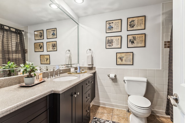 bathroom featuring tile patterned floors, vanity, toilet, and tile walls