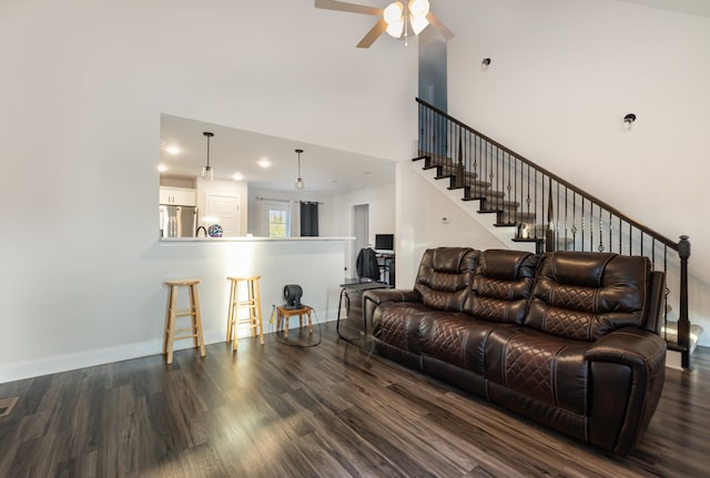 living room featuring a high ceiling, dark hardwood / wood-style floors, and ceiling fan