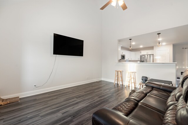 living room featuring ceiling fan, dark wood-type flooring, and a high ceiling