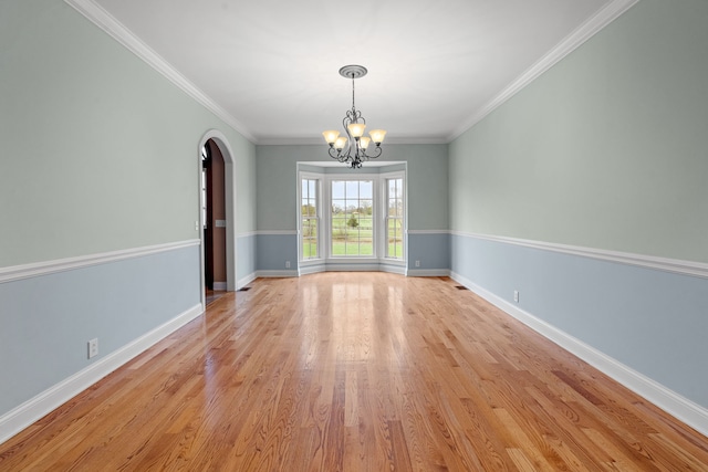 unfurnished dining area featuring light wood-type flooring, ornamental molding, and a notable chandelier