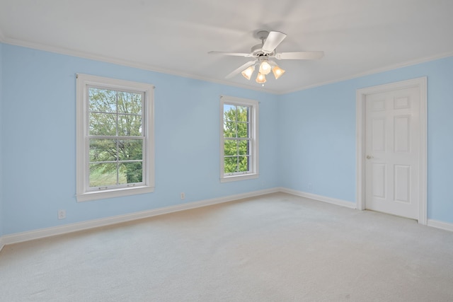 spare room featuring ceiling fan, light colored carpet, ornamental molding, and a wealth of natural light