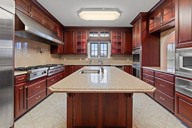 kitchen featuring built in appliances, sink, a kitchen island with sink, and a breakfast bar area