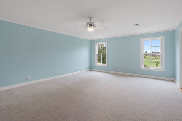 carpeted spare room featuring a wealth of natural light, crown molding, and ceiling fan