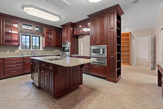 kitchen with decorative backsplash, appliances with stainless steel finishes, a kitchen island with sink, crown molding, and sink