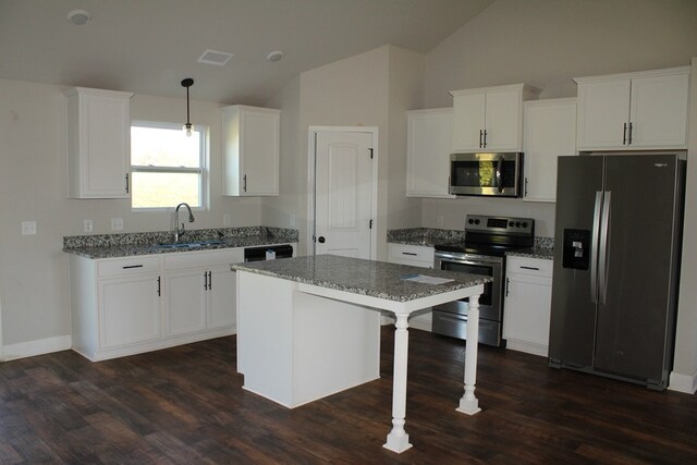 kitchen with stainless steel appliances, sink, light stone counters, hanging light fixtures, and a kitchen island