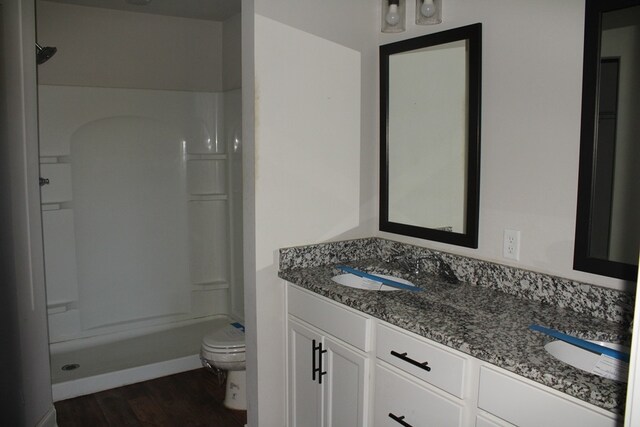 bathroom with toilet, wood-type flooring, vanity, and walk in shower