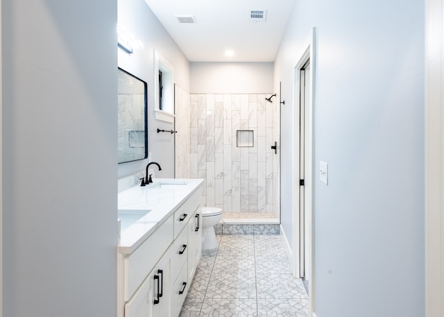 bathroom featuring a tile shower, tile patterned floors, vanity, and toilet