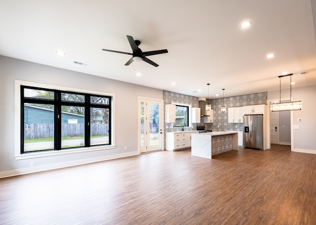 kitchen with hardwood / wood-style floors, decorative light fixtures, stainless steel fridge with ice dispenser, a center island, and white cabinetry