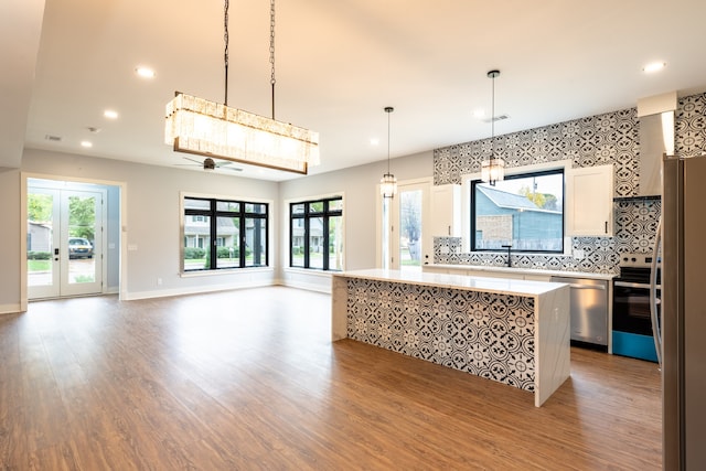 kitchen featuring appliances with stainless steel finishes, ceiling fan, a healthy amount of sunlight, and wood-type flooring